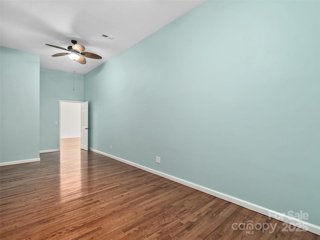 empty room featuring a ceiling fan, wood finished floors, visible vents, and baseboards