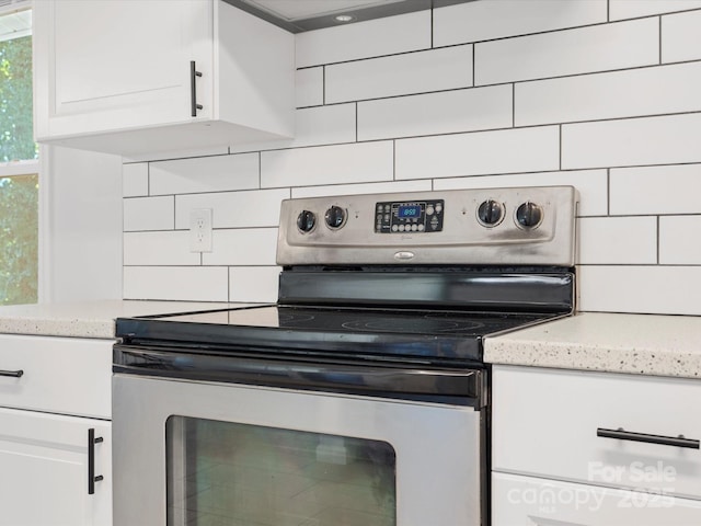 kitchen featuring tasteful backsplash, white cabinets, stainless steel electric range oven, and light stone countertops