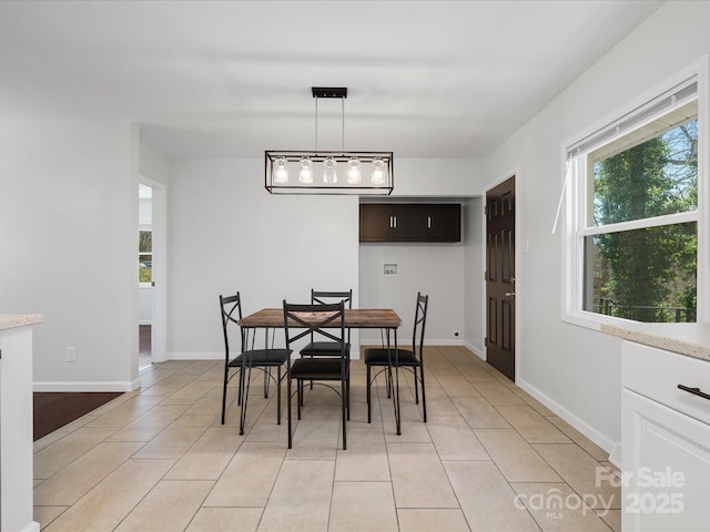 dining space featuring light tile patterned flooring and baseboards