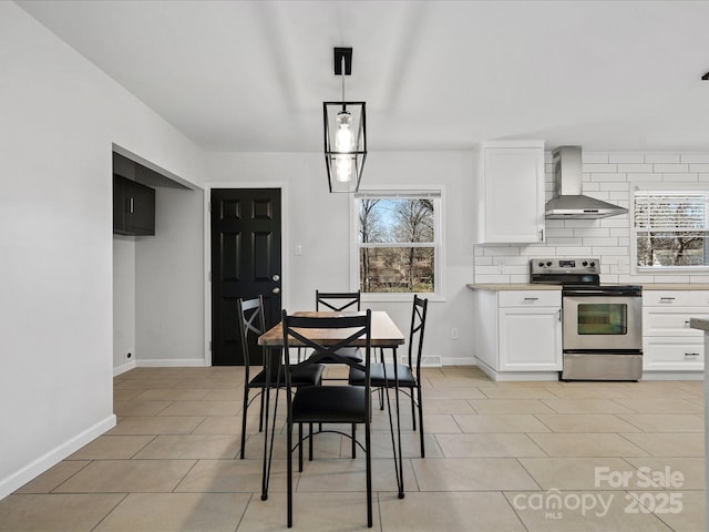 kitchen with electric stove, wall chimney range hood, white cabinets, and tasteful backsplash