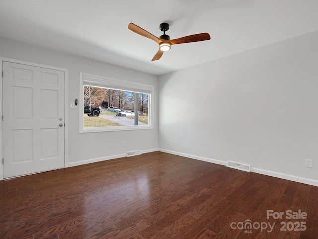 unfurnished room featuring dark wood-style flooring, visible vents, and baseboards