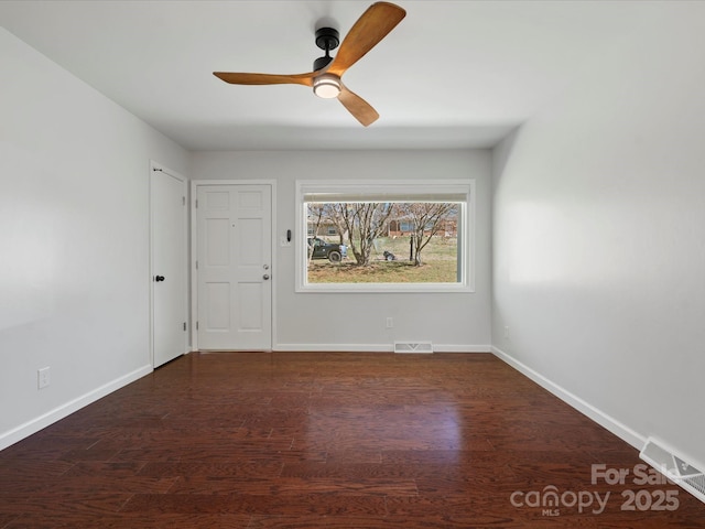 empty room with baseboards, visible vents, and wood finished floors