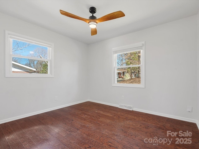 spare room featuring ceiling fan, dark wood-type flooring, visible vents, and baseboards