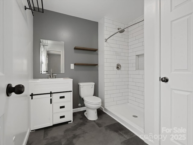 full bathroom with baseboards, tiled shower, vanity, and toilet