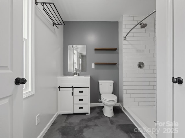 full bathroom with tiled shower, vanity, toilet, and baseboards