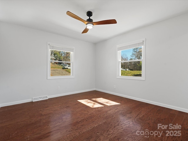 empty room with a wealth of natural light, visible vents, and wood finished floors