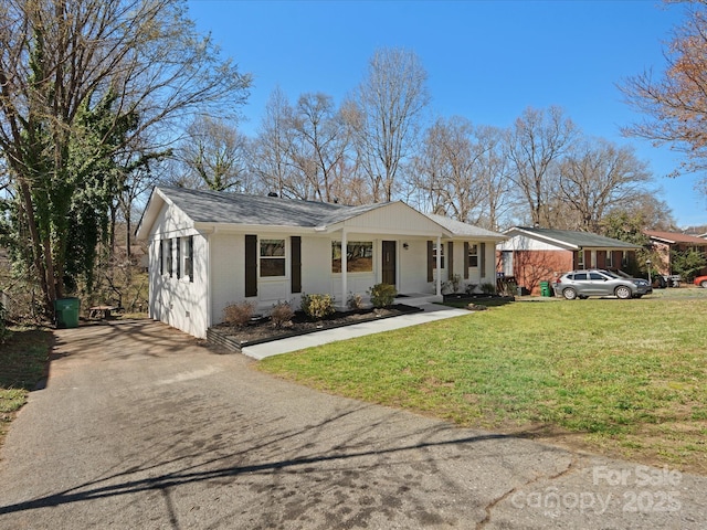 ranch-style home featuring driveway, roof with shingles, a front yard, and brick siding