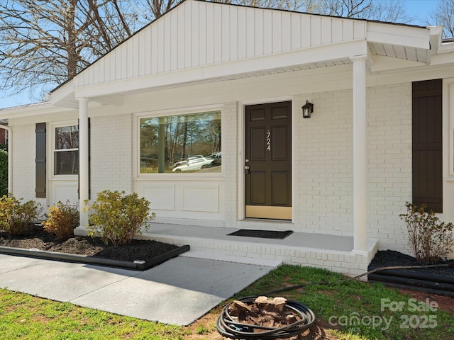 doorway to property with brick siding and a porch