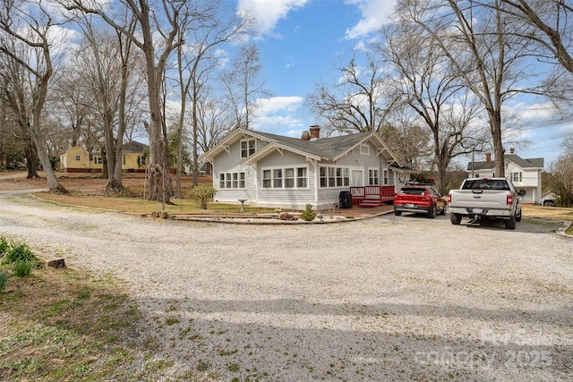 view of front of home with gravel driveway and a chimney