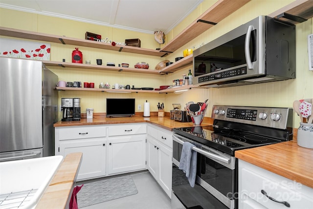 kitchen with stainless steel appliances, white cabinetry, ornamental molding, and wood counters