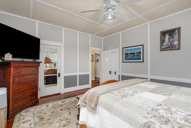 bedroom featuring ceiling fan, coffered ceiling, wood finished floors, and a decorative wall