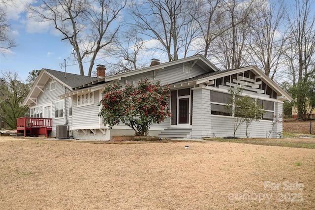 view of front facade with entry steps, a chimney, a deck, central air condition unit, and a front lawn