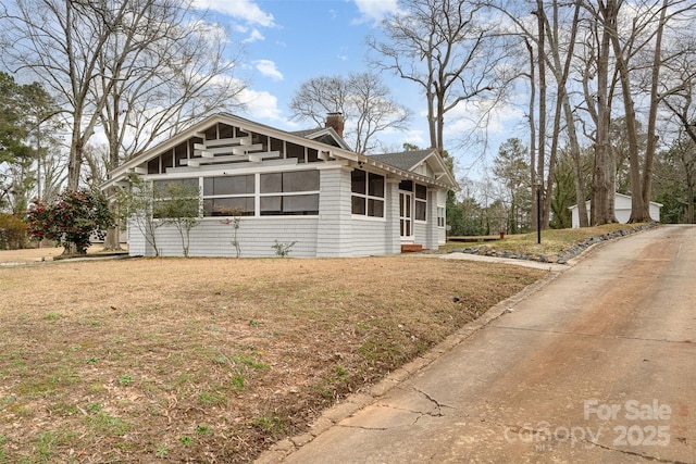 view of front of home with a front lawn, a chimney, and a sunroom