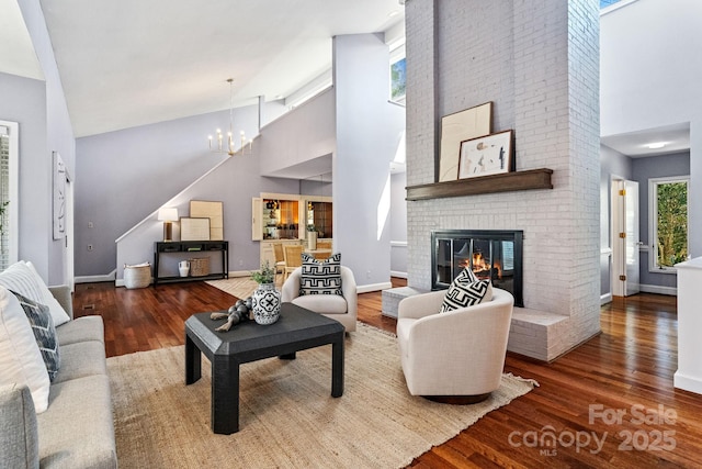 living area featuring an inviting chandelier, a fireplace, high vaulted ceiling, and wood finished floors