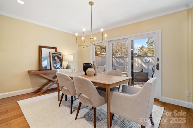 dining room featuring a chandelier, crown molding, light wood-style flooring, and baseboards