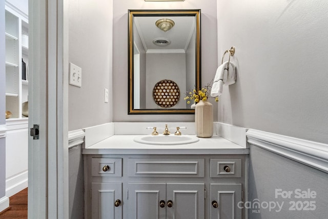 bathroom featuring wainscoting, vanity, visible vents, and crown molding