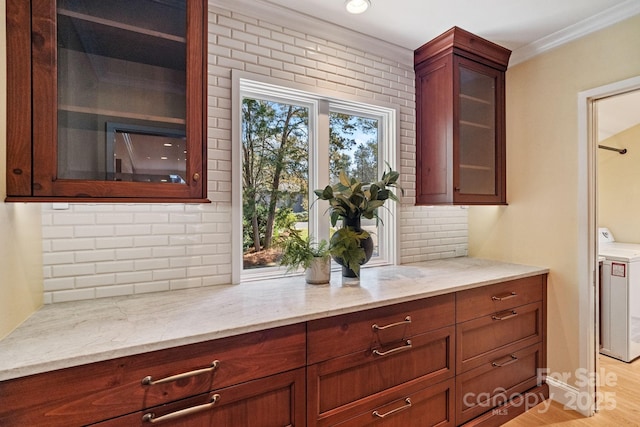 kitchen featuring washer / dryer, glass insert cabinets, decorative backsplash, and light stone counters