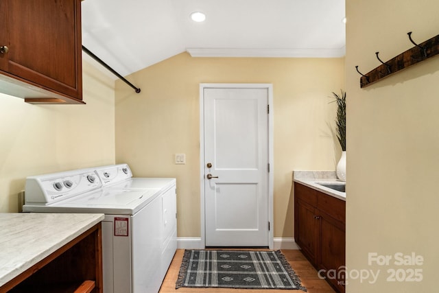 laundry area with light wood-style floors, baseboards, washer and dryer, cabinet space, and crown molding