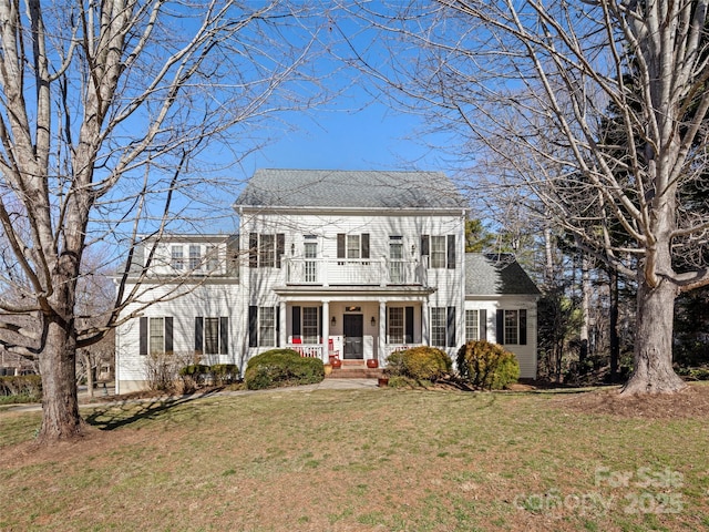 colonial house with covered porch, a shingled roof, a front yard, and a balcony