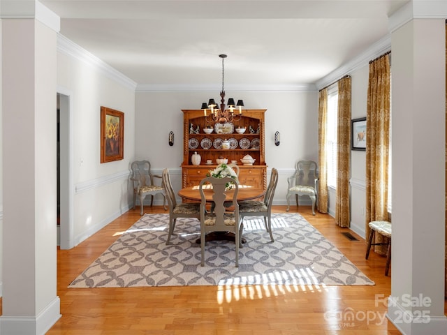 dining area with ornamental molding, light wood-type flooring, visible vents, and a notable chandelier