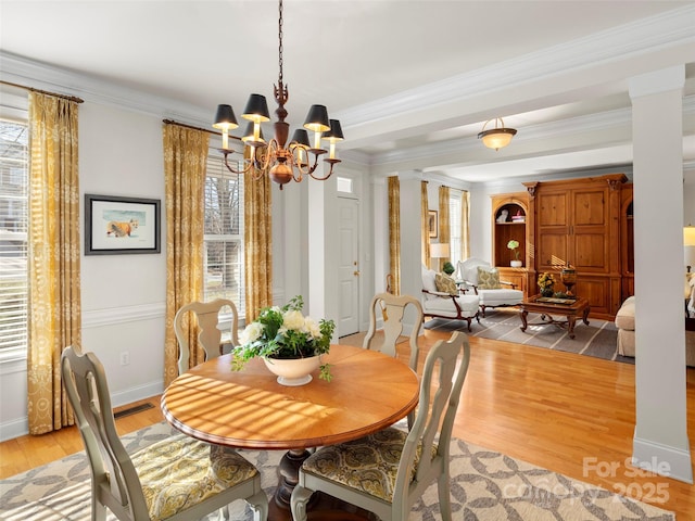 dining area with baseboards, light wood-style flooring, a chandelier, and crown molding