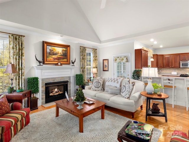 living room with light wood finished floors, a fireplace with flush hearth, high vaulted ceiling, and recessed lighting