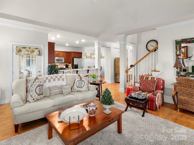 living area featuring decorative columns, stairway, light wood-style flooring, ornamental molding, and baseboards