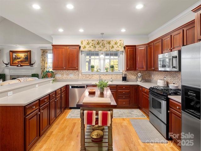 kitchen featuring ornamental molding, light countertops, appliances with stainless steel finishes, and light wood-type flooring