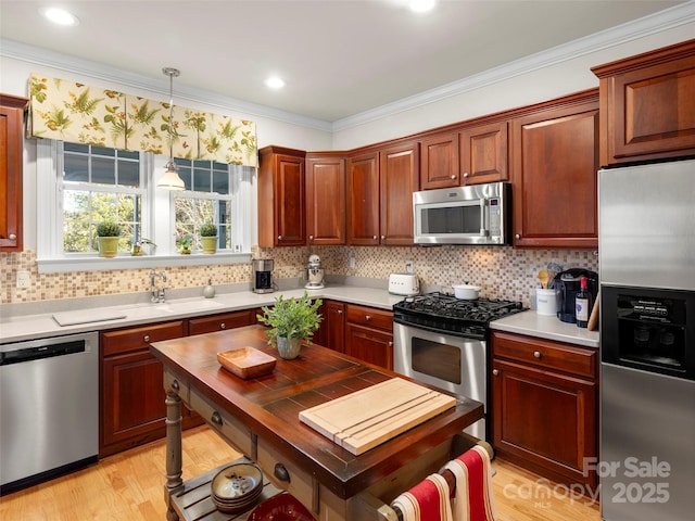 kitchen with decorative backsplash, appliances with stainless steel finishes, ornamental molding, light countertops, and light wood-type flooring