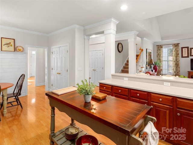 kitchen with dark brown cabinets, ornamental molding, light countertops, and light wood-style floors