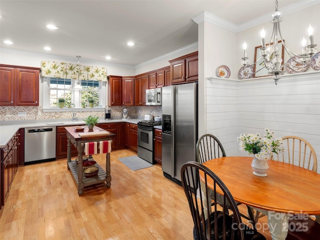 kitchen with tasteful backsplash, appliances with stainless steel finishes, light wood-style flooring, and decorative light fixtures