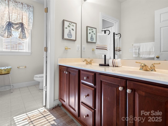 bathroom featuring double vanity, toilet, a sink, and tile patterned floors