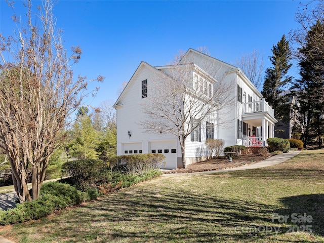 view of side of property with a garage, a yard, and a balcony