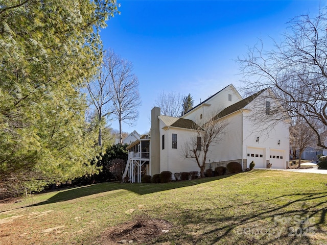 view of side of property with a chimney, concrete driveway, and a yard