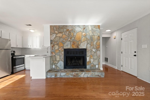 unfurnished living room featuring a fireplace, wood finished floors, visible vents, and crown molding