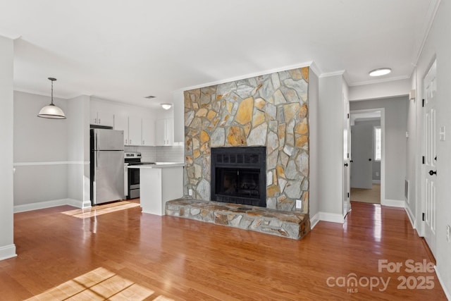 unfurnished living room with baseboards, a fireplace, ornamental molding, and wood finished floors