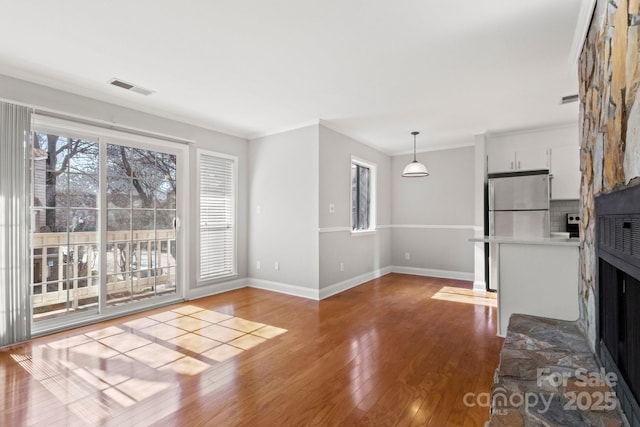 unfurnished living room featuring ornamental molding, hardwood / wood-style floors, a fireplace, and visible vents