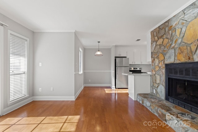 unfurnished living room featuring light wood finished floors, visible vents, baseboards, crown molding, and a fireplace