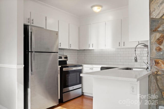 kitchen featuring appliances with stainless steel finishes, white cabinets, a sink, and tasteful backsplash