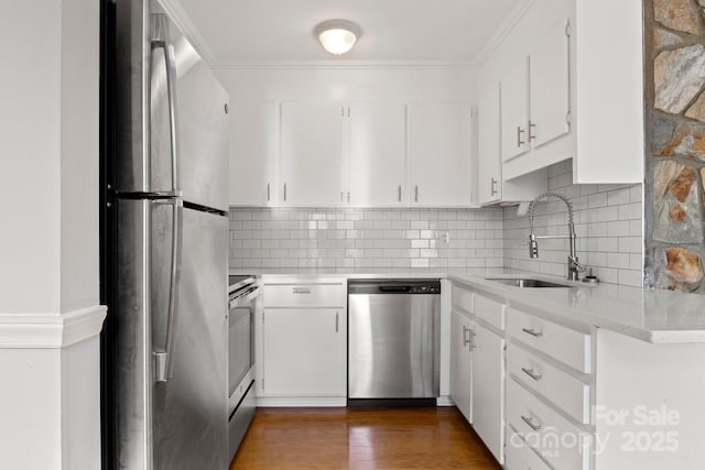 kitchen featuring appliances with stainless steel finishes, white cabinets, a sink, and wood finished floors