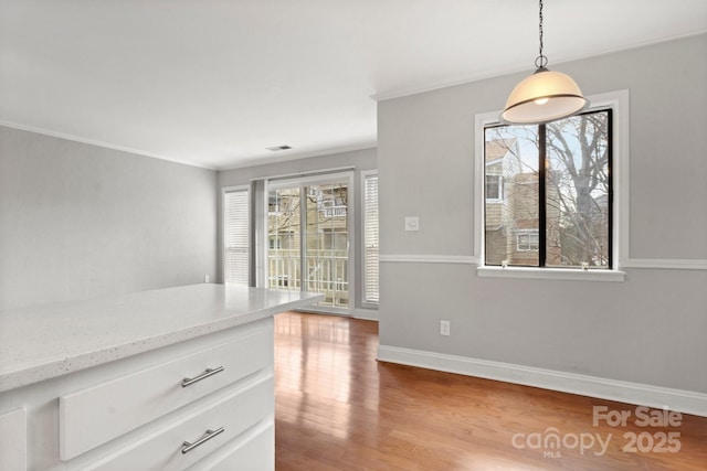 unfurnished dining area featuring ornamental molding, light wood-type flooring, and baseboards