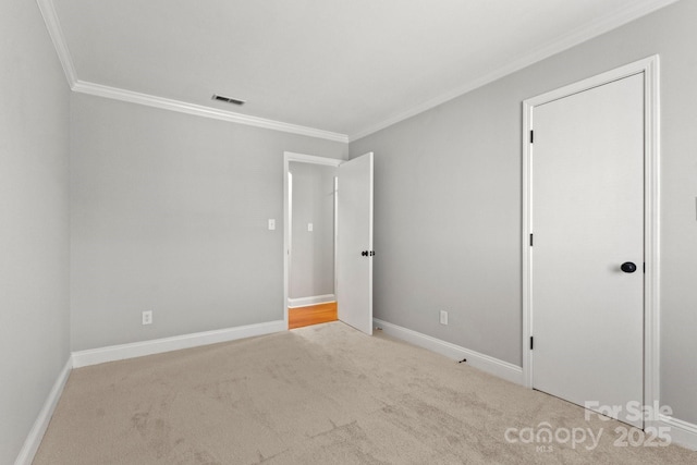 unfurnished bedroom with carpet, visible vents, crown molding, and baseboards