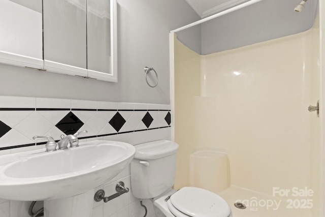 bathroom featuring tile walls, a sink, a shower stall, and toilet