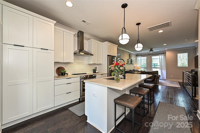 kitchen featuring visible vents, wall chimney range hood, backsplash, and appliances with stainless steel finishes