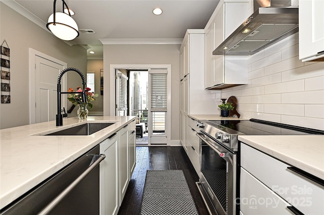 kitchen featuring tasteful backsplash, white cabinets, wall chimney exhaust hood, appliances with stainless steel finishes, and a sink