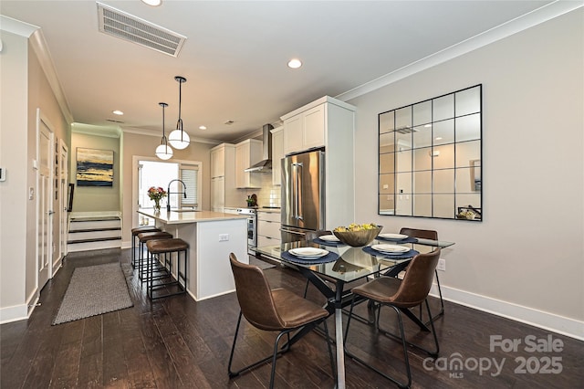 dining space with dark wood-style floors, visible vents, and crown molding