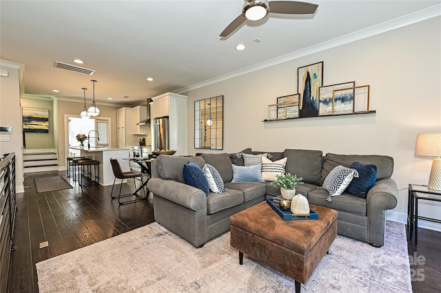 living room featuring dark wood-style flooring, recessed lighting, visible vents, stairway, and ornamental molding