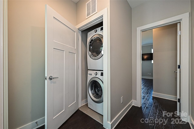 washroom with dark wood-style floors, laundry area, visible vents, and stacked washer / dryer