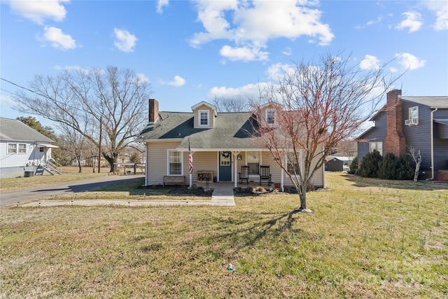 view of front of property featuring a front yard, covered porch, and a chimney