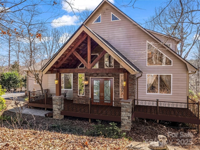 back of house featuring a deck, french doors, and stone siding